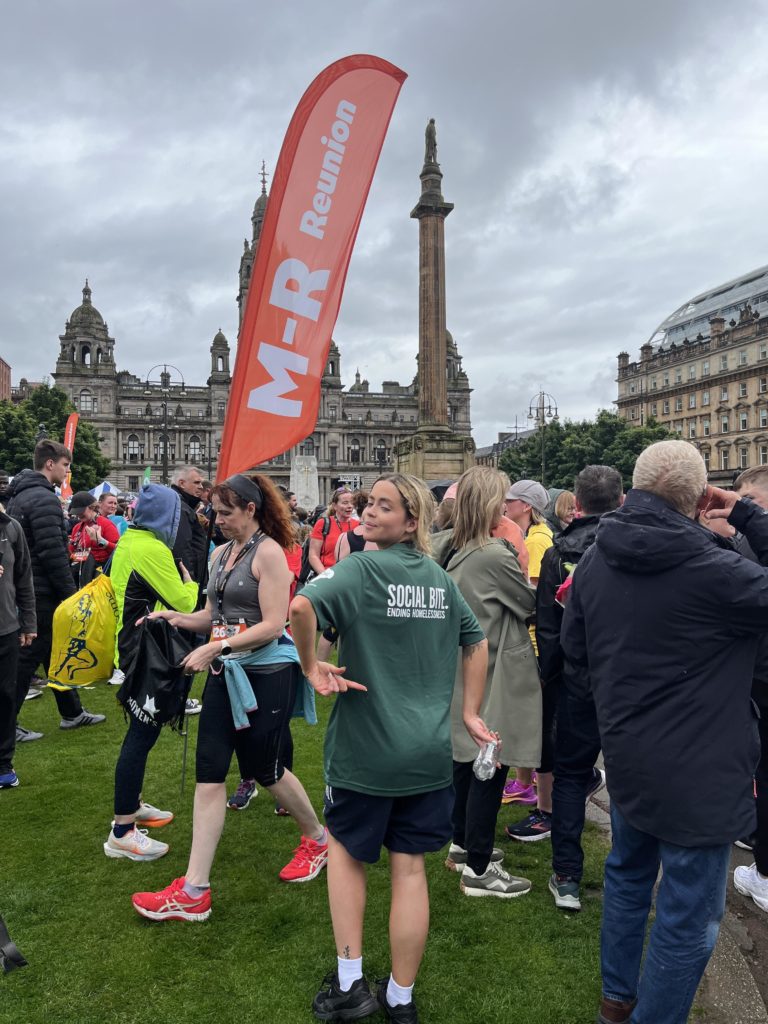 a young woman in a Social Bite tshirt looks over her shoulder before her 10k race begins